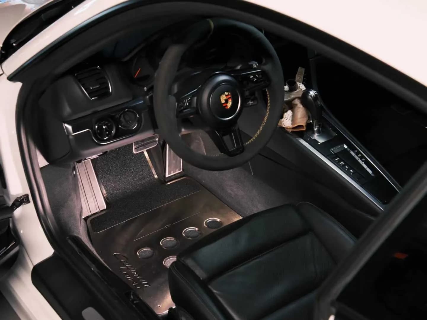 Actual perforated metal floor mat set viewed across a black vehicle interior