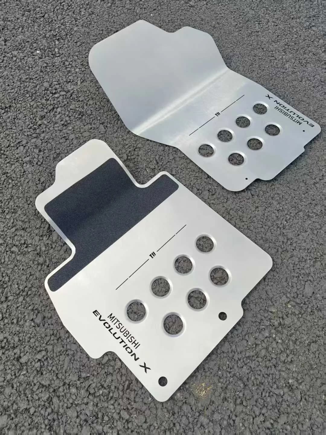 Actual compact metal floor mat pair combining perforated and ribbed details