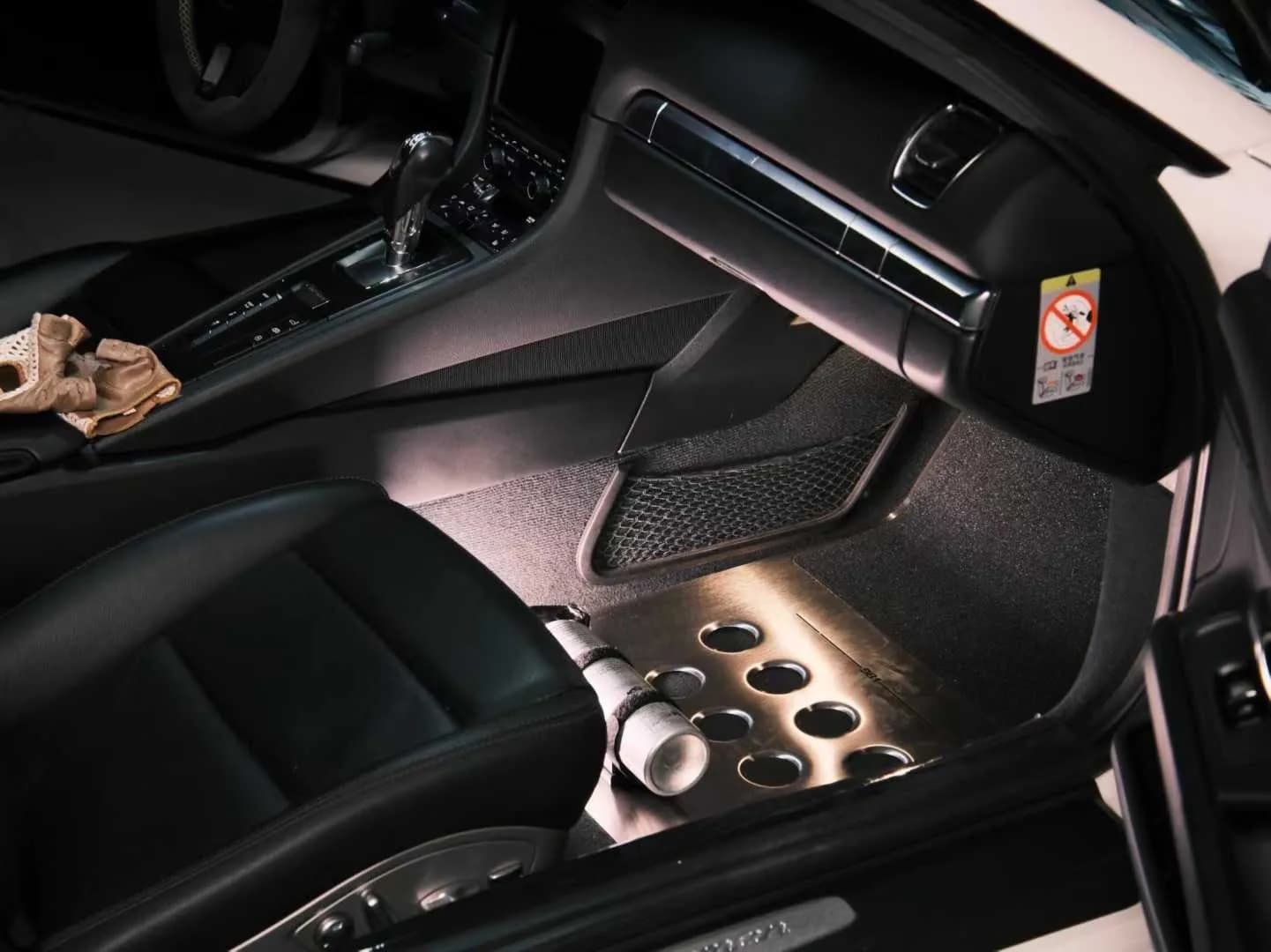 Close view of an actual perforated metal floor mat installed beside a seat