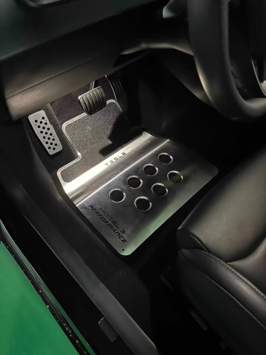 Custom brushed stainless steel driver floor mat installed in a Tesla Model 3